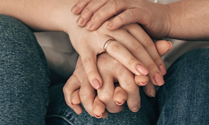 Two pairs of hands resting one on top of the other in support